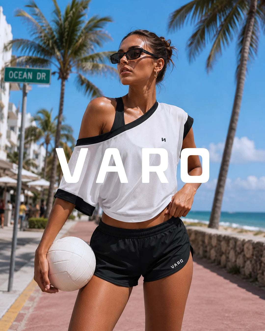 Woman holding a volleyball on a beach with palm trees and 'VARO' branding.