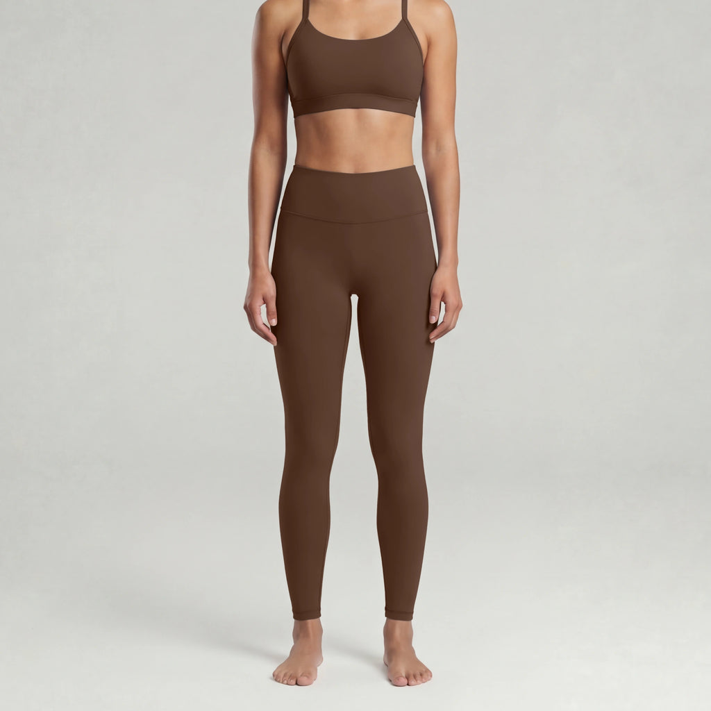 A woman wearing a chocolate brown sports bra and leggings