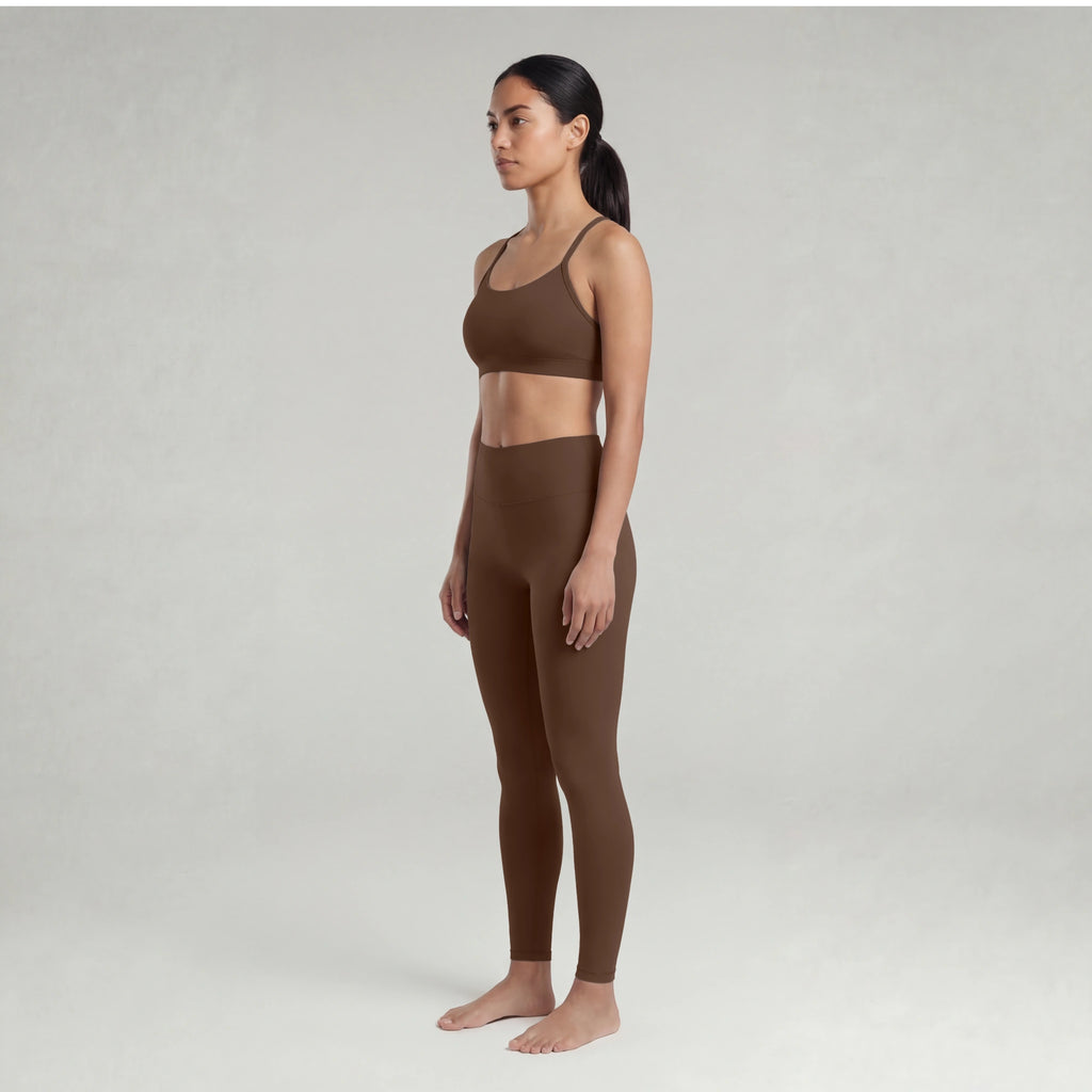 A woman wearing a chocolate brown sports bra and leggings