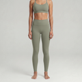 A woman is wearing a sage green leggings and a sage green sports bra top 