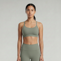 A woman is wearing a sage green brown  sports bra and pants