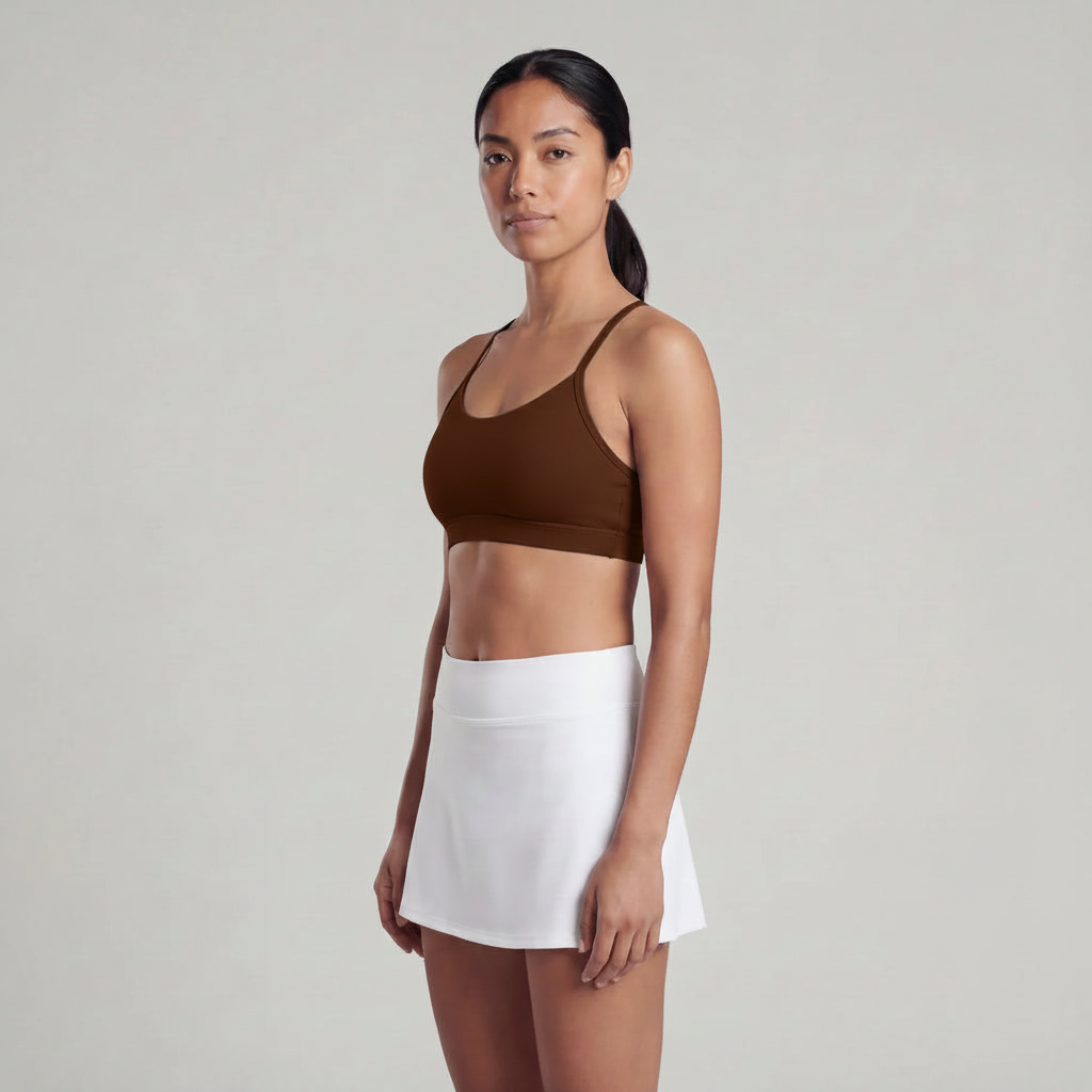 A woman is wearing a black skirt and a chocolate brown sports bra top 