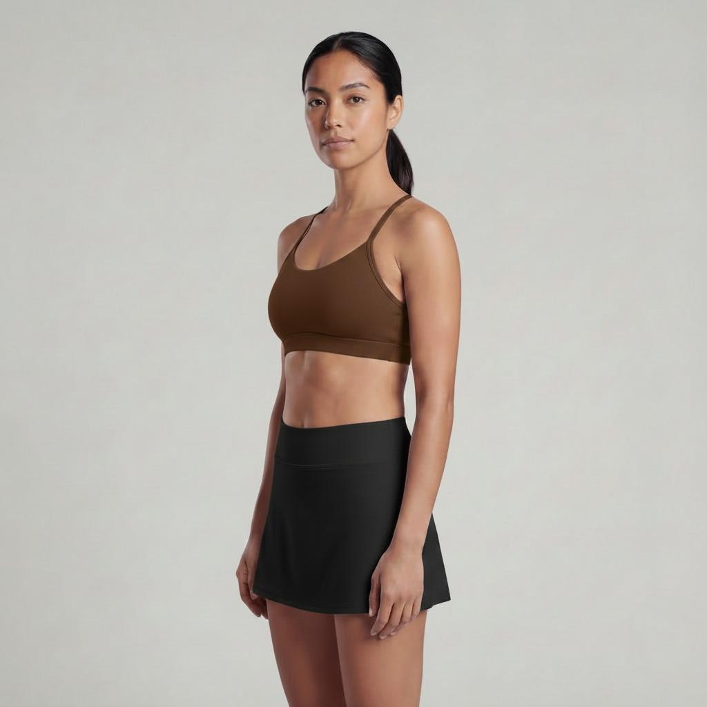 A woman is wearing a black skirt and a chocolate brown sports bra top 