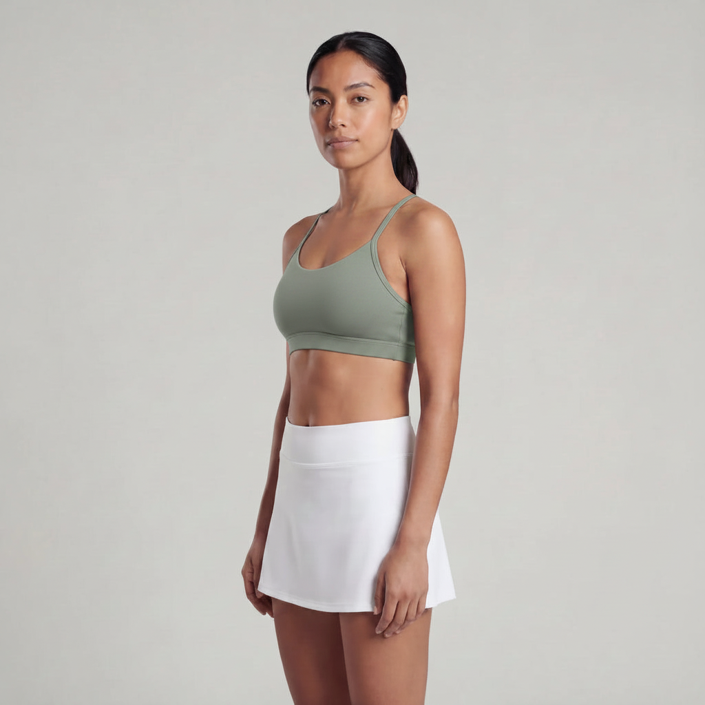 A Woman wearing a sage green sports bra and a white skirt 