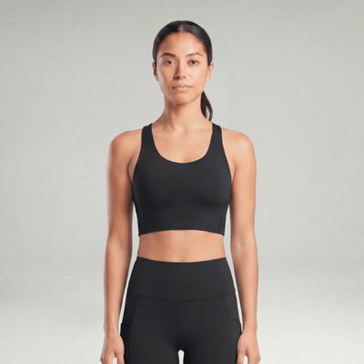 Woman wearing a black sports bra and leggings on a gray background