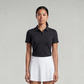 Woman wearing a black polo shirt and white skirt on a gray background