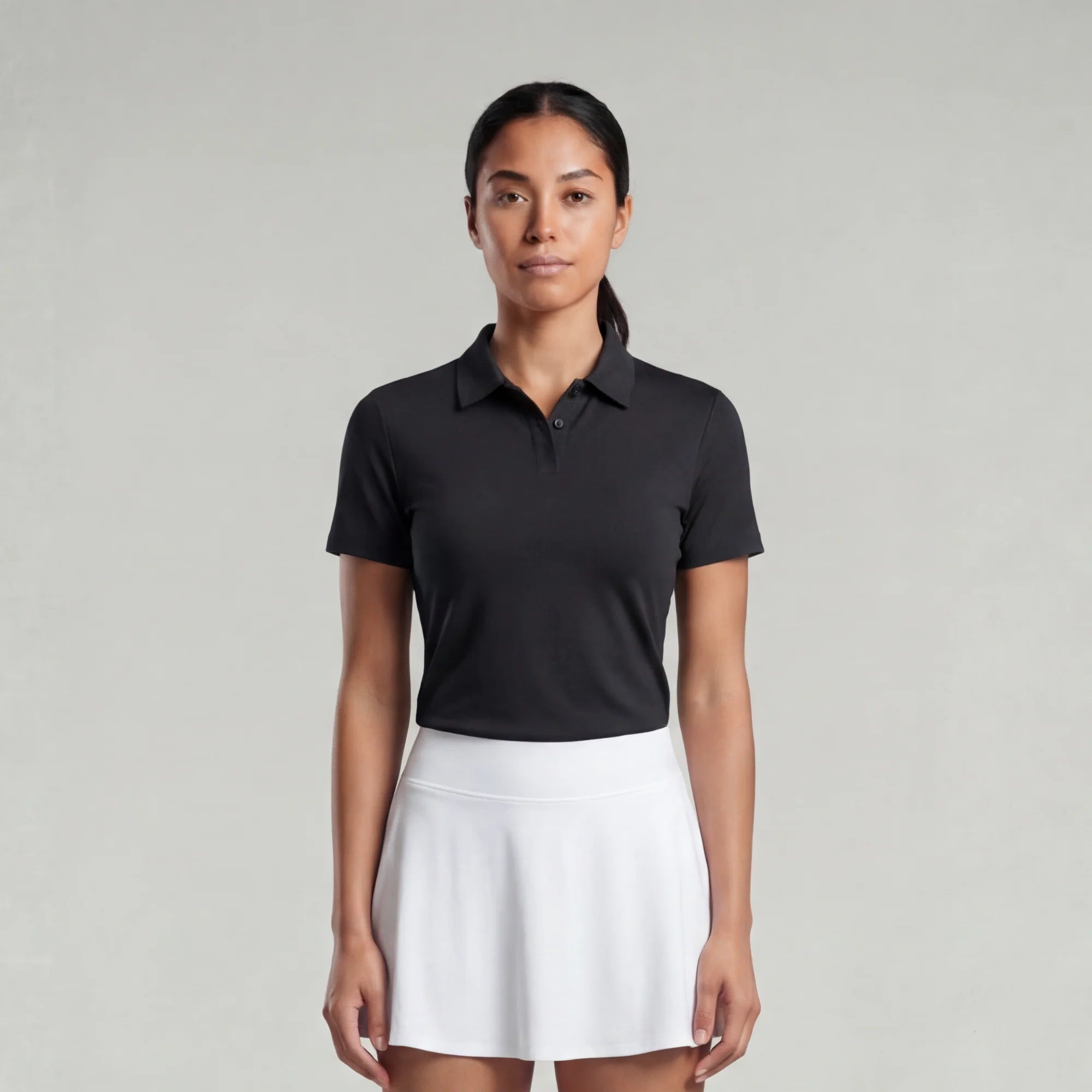 Woman wearing a black polo shirt and white skirt on a gray background